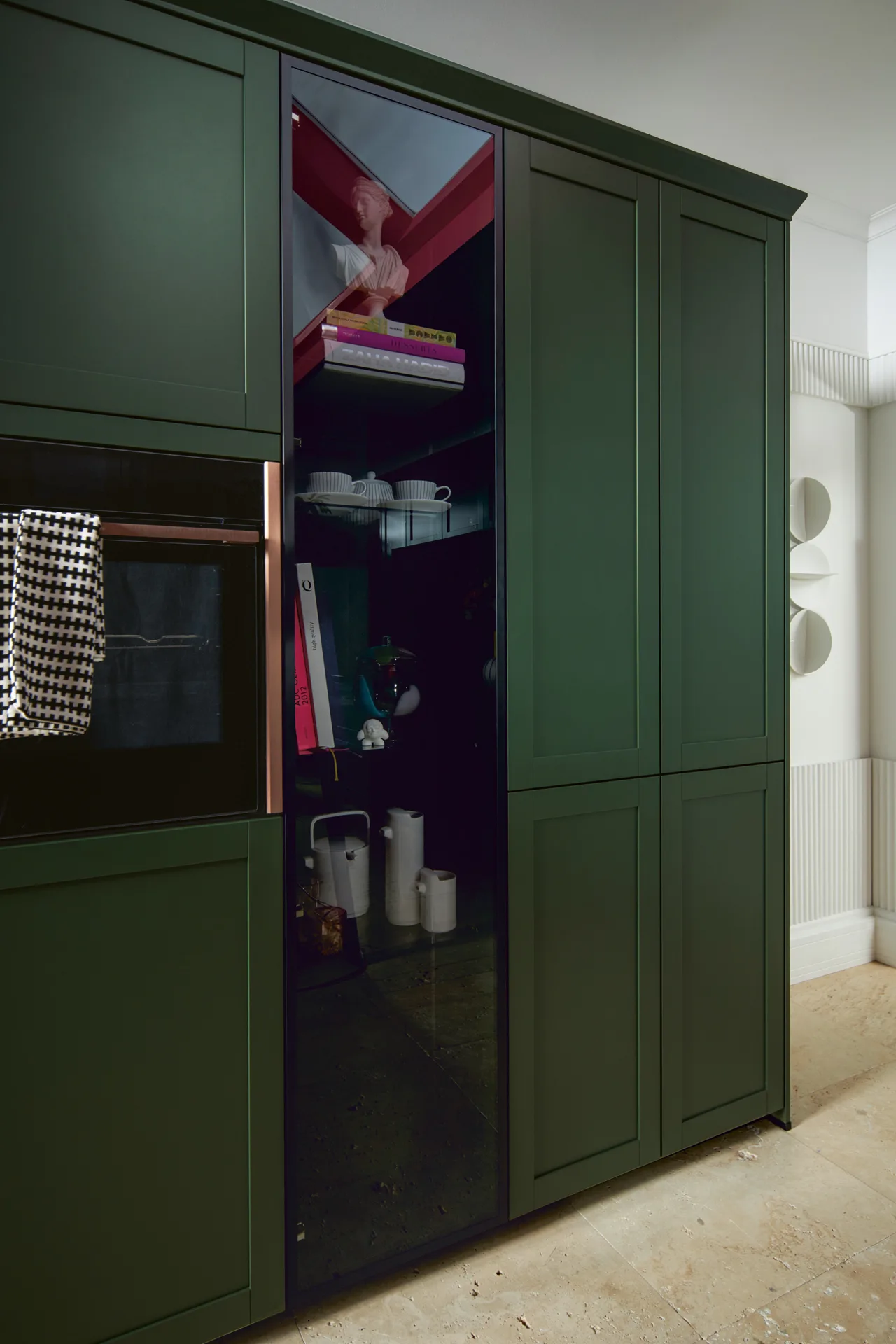 Grüner Küchen-Hochschrank mit kupferfarbenem Backofen und beleuchteter Glasvitrine — Miller Küchen